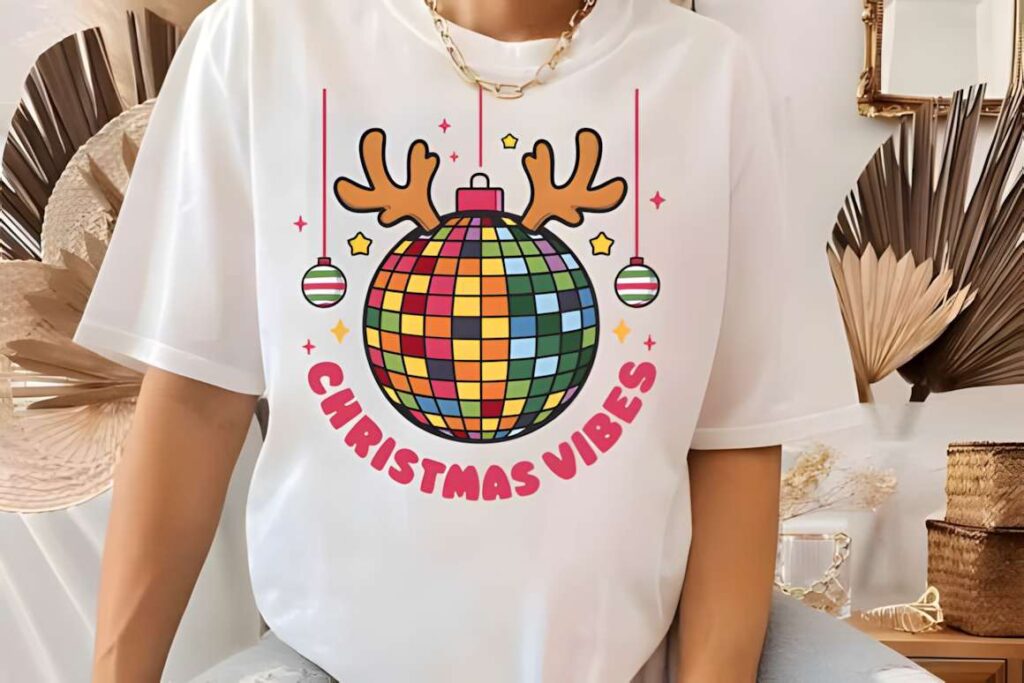 Christmas T-shirt design ideas for POD sellers featuring a colorful disco ball with reindeer antlers and ornaments
